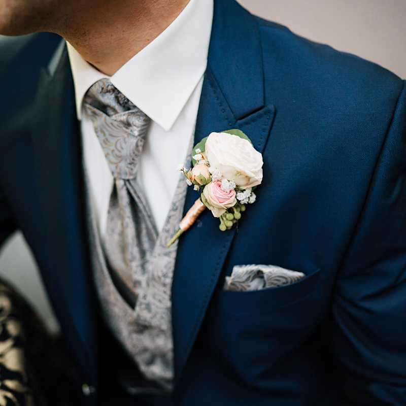 Ein Mann trägt einen blauen Anzug mit silbergrauer Weste und gemusterter Krawatte