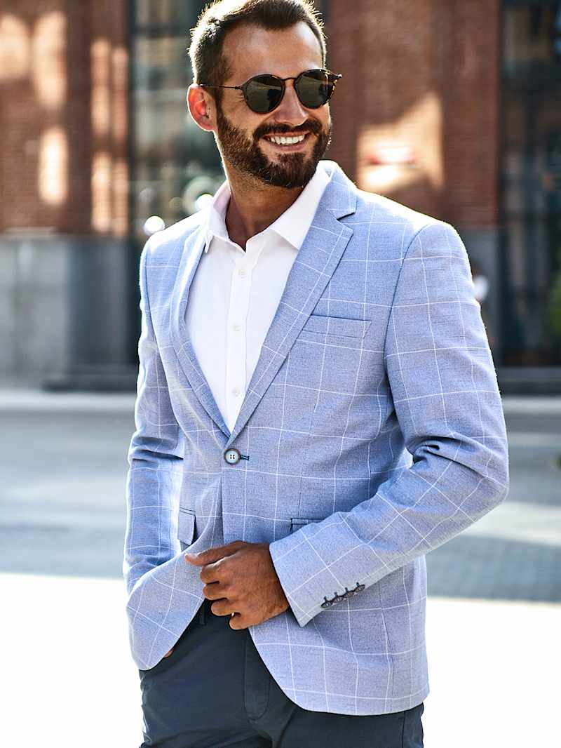 Mężczyzna w białej koszuli bez krawata i błękitnej marynarce w szeroką kratkę