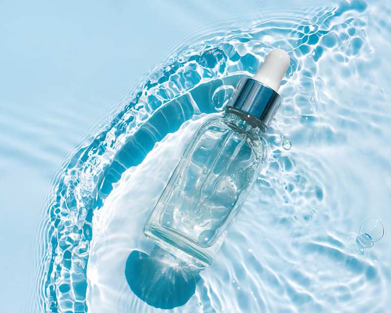 Serum-Flasche auf einem wasserbettähnlichen Untergrund vor blauem Hintergrund