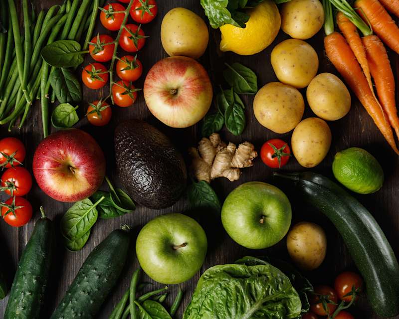 Auswahl an frischem Gemüse wie Tomaten, Gurken, Karotten und Paprika, angeordnet auf dunklem Holzuntergrund, Flatlay-Fotografie.