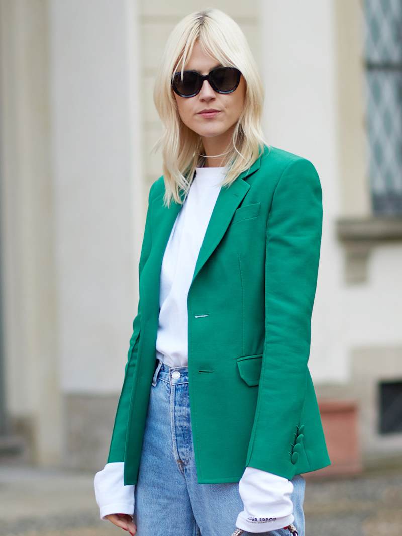 Blonde Frau trägt einen grünen Blazer zu einem weißen Shirt und Blue Jeans