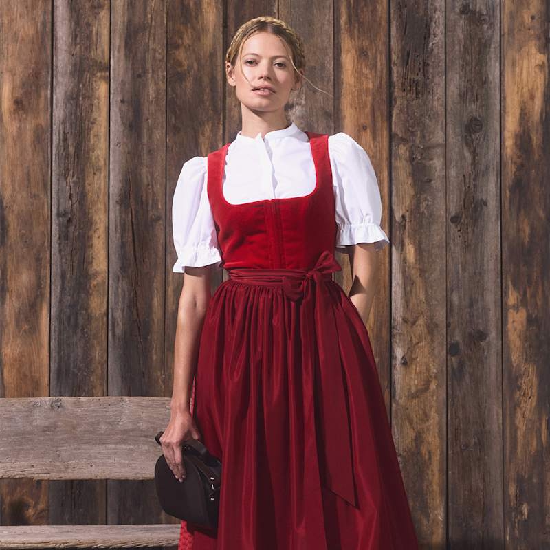Blonde Frau trägt rotes Dirndl mit Schleife