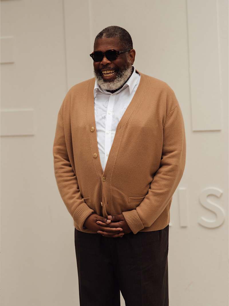 Mann trägt eine beige Strickjacke zu einer schwarzen Hose