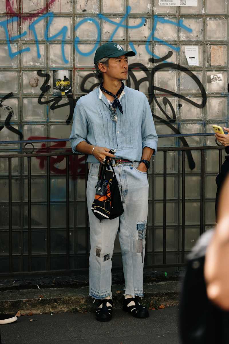 Mann trägt eine Destroyed Denim mit einem hellblauen Hemd und grünem Cap. 