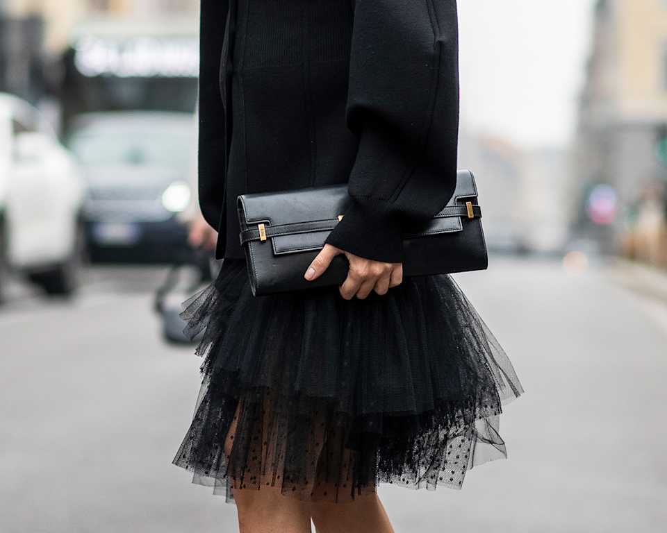 Frau trägt schwarze Clutch zu schwarzem Outfit