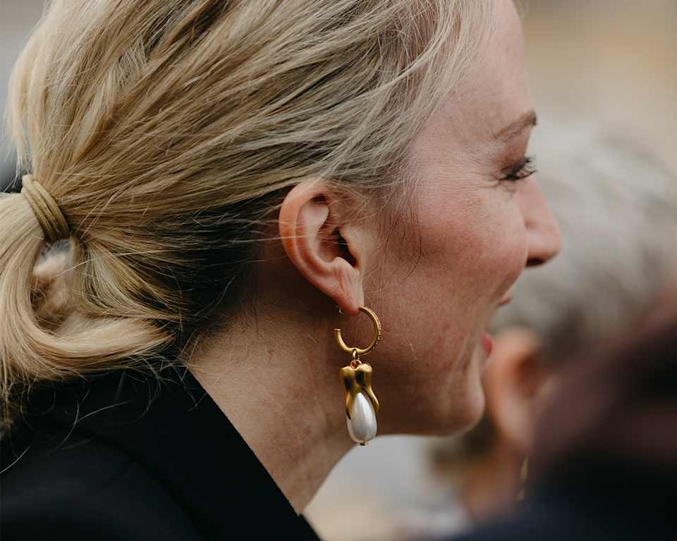Blonde Frau trägt goldene Ohrhänger mit Perle