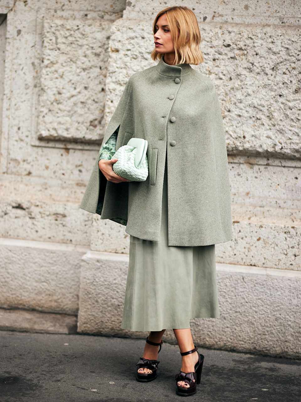 Frau trägt eine Clutch und einen salbeigrünen Cape