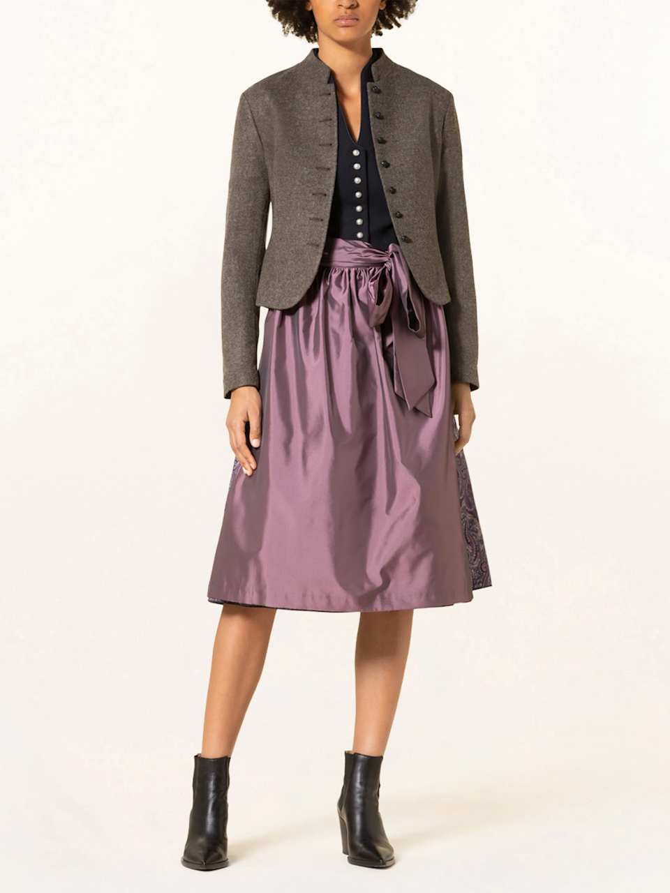 Frau trägt festliches Dirndl mit roséfarbener Schürze und Trachtenjacke