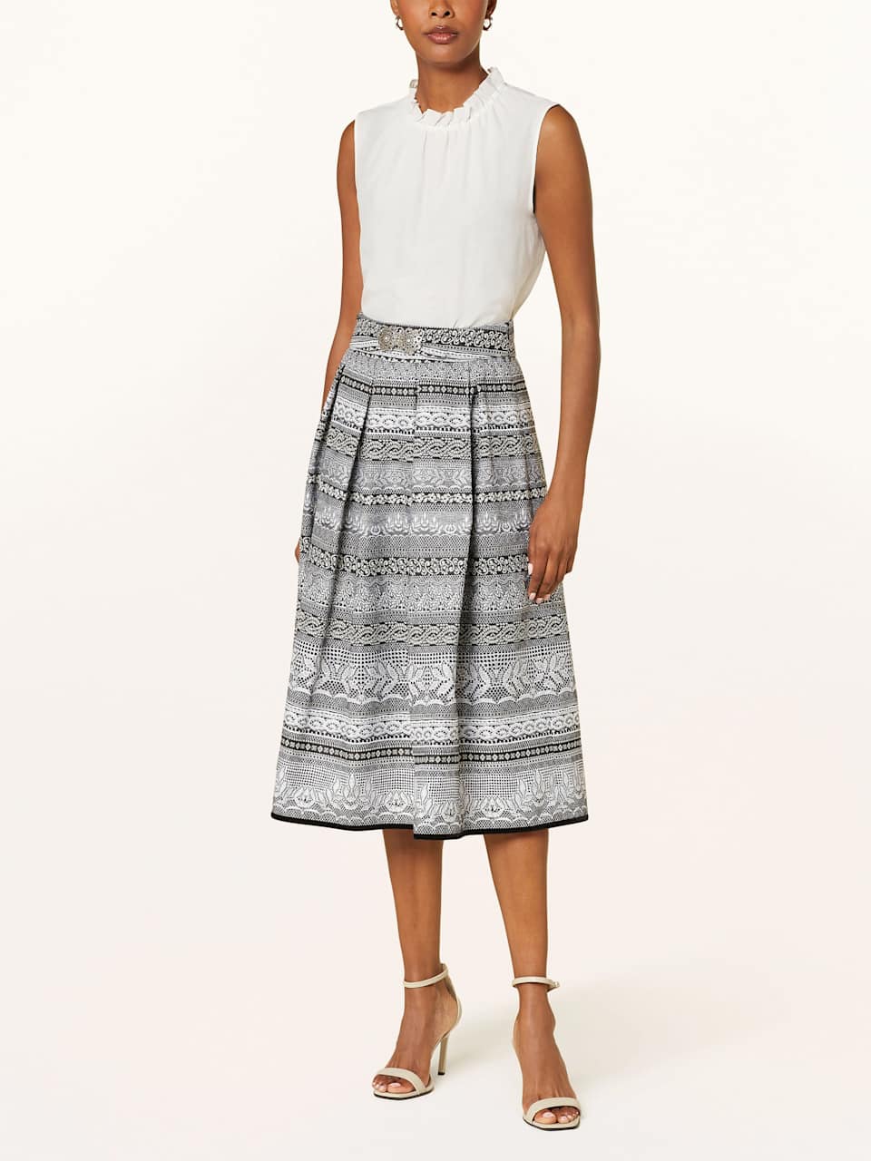 Frau trägt gemusterten Trachtenrock mit weißer Bluse