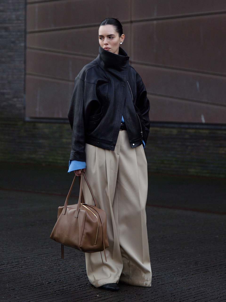 Frau trägt Lederjacke mit Stehkragen und eine beige Stoffhose