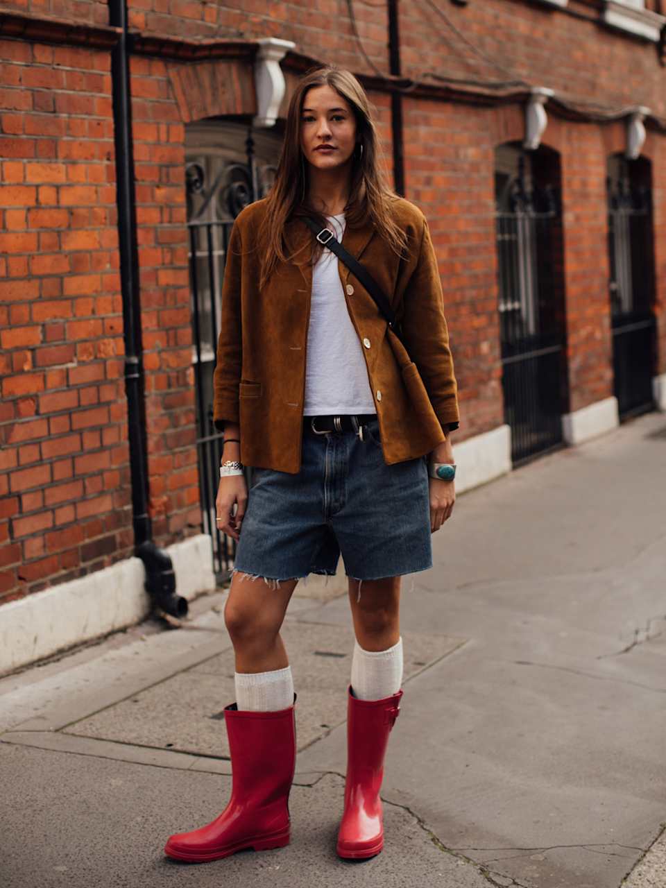 Frau trägt rote Gummistiefel zur einer Jeans-Shorts und braunem Lederhemd