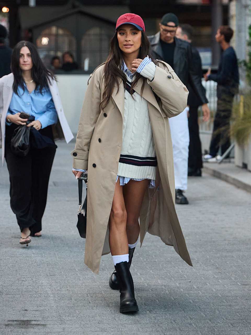 Frau trägt einen Trenchcoat, Strickpullover und Boots