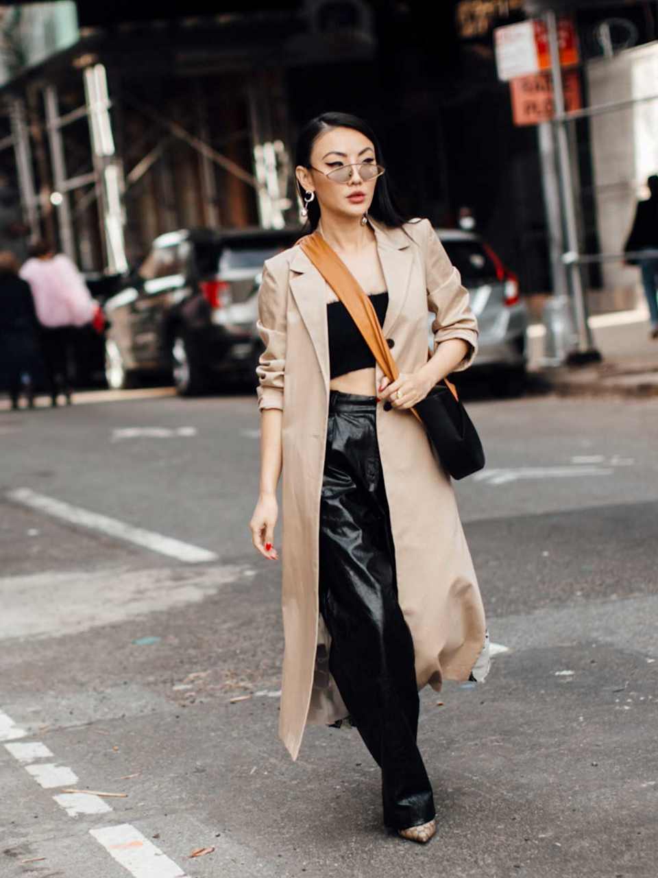 Frau trägt zu einer schwarzen Lederhose ein Copped Top und Trenchcoat