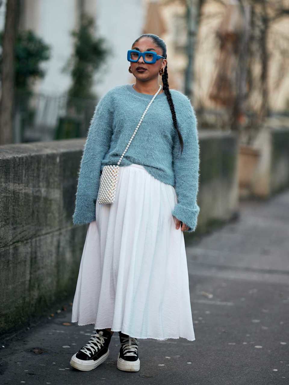 Frau kombiniert zu einem Plisseerock dunkle Sneaker