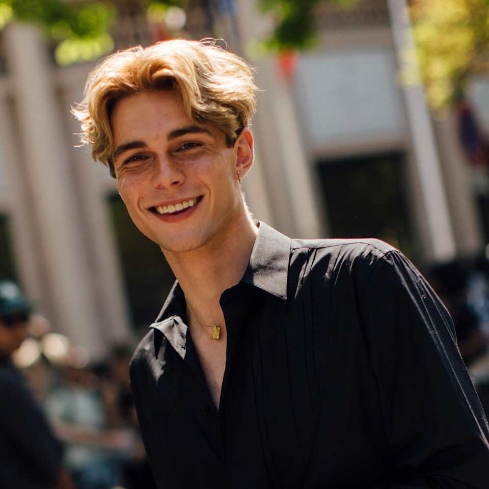 Blonder Mann trägt sein mittellanges Haar im Mittelscheitel