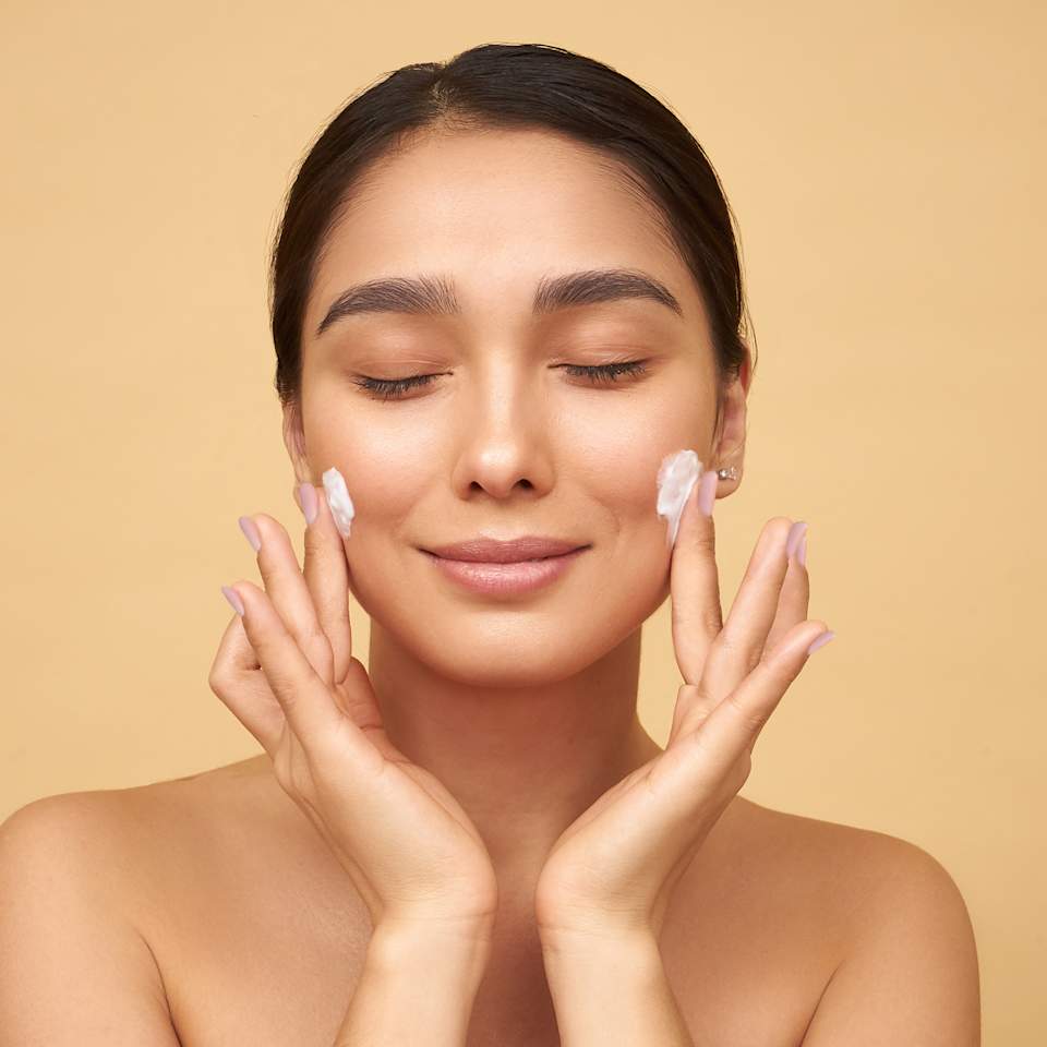 Brünette Frau cremt sich das Gesicht ein