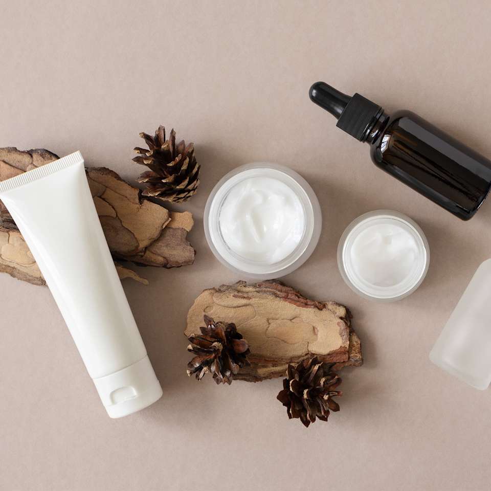 Verschiedene Pflegeprodukte auf sandfarbenem Hintergrund