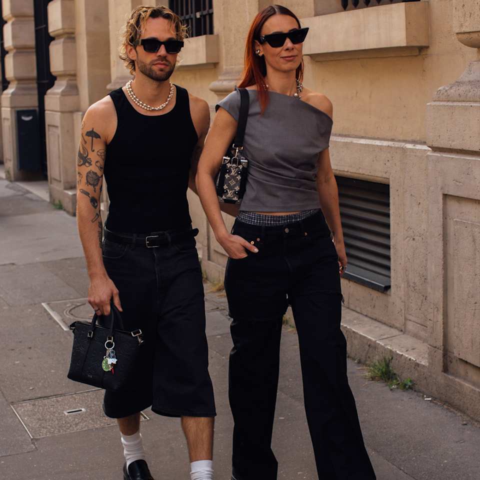 Mann trägt ein schwarzes Top und eine schwarze Hose und die Frau ein graues Top und lange Hose im Y2K-Style