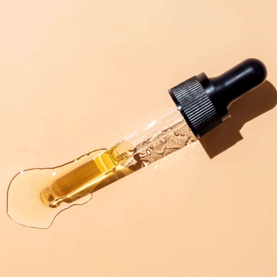 Pipette mit schwarzem Griff und goldener Flüssigkeit