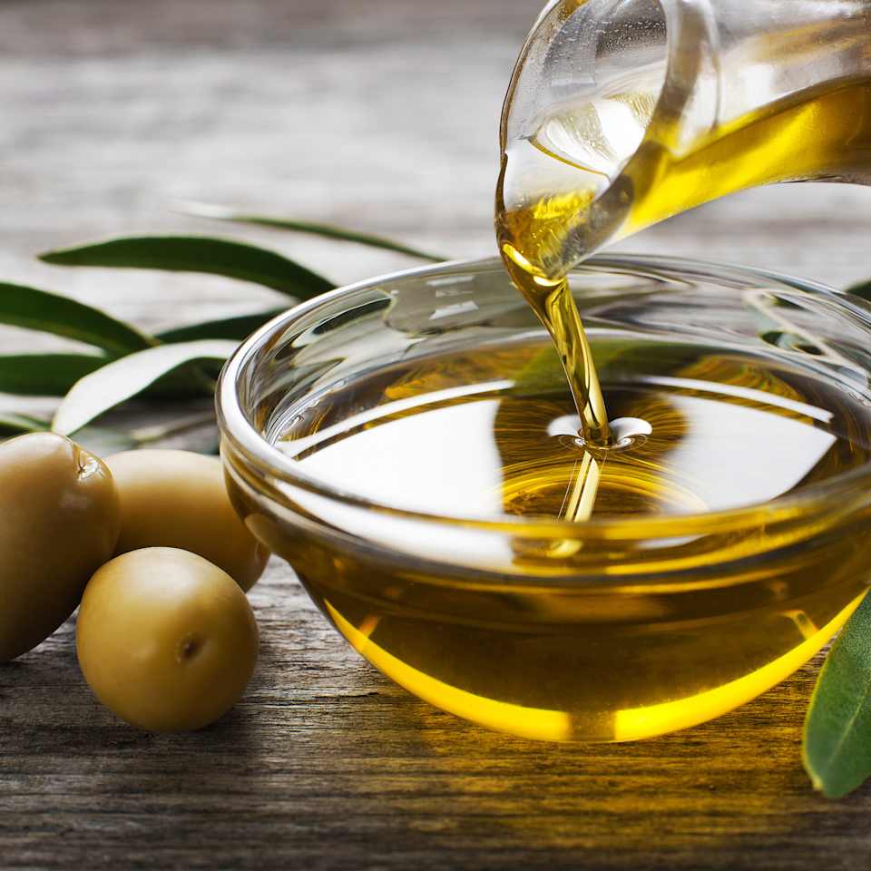 Schale mit Olivenöl und grünen Oliven