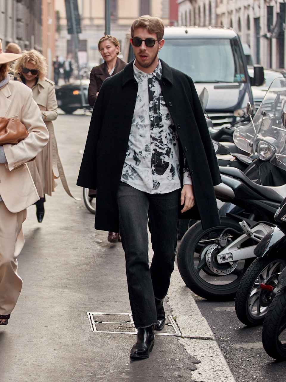 Mann trägt Hemd mit Batikmuster, dazu einen schwarzen Mantel, dunkelgraue Stone Washed Jeans und Biker Boots