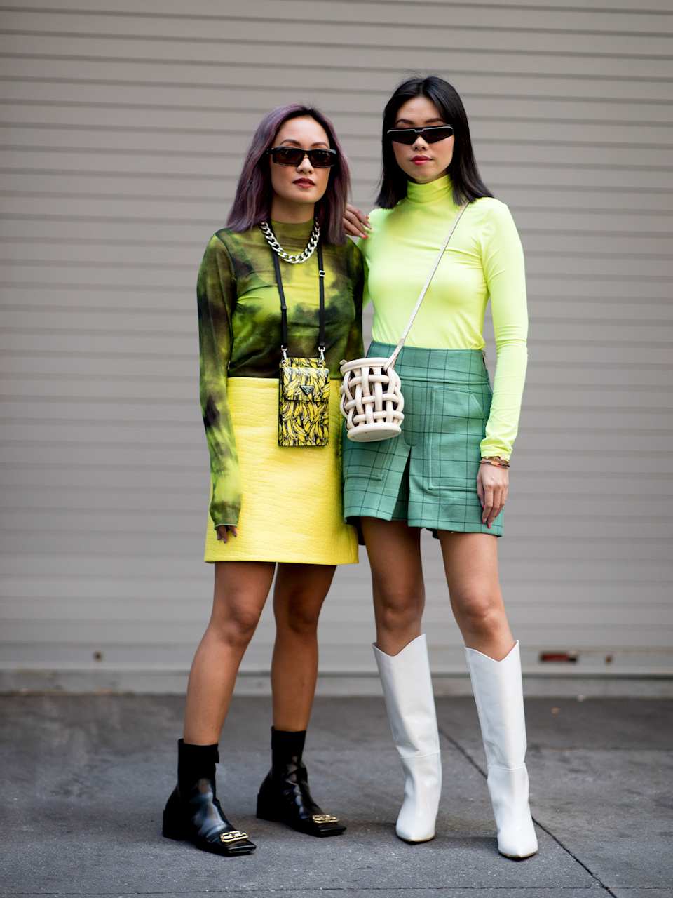 Zwei Frauen tragen kürze Röcke zu modischen grün-gelben Outfits.