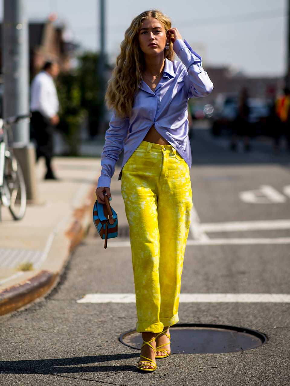 Frau trägt gelbe Hose mit Batikmuster zu blauem Hemd und Sandalen