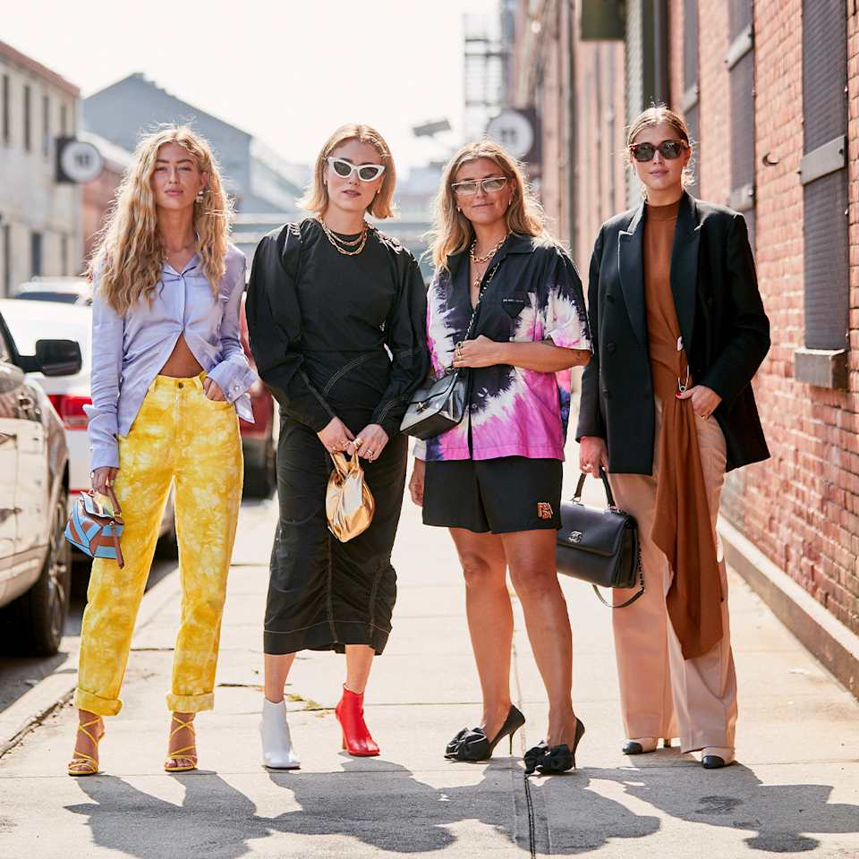 Vier modisch gekleidete Frauen stehen auf dem Fußweg bereit für den Sommer.