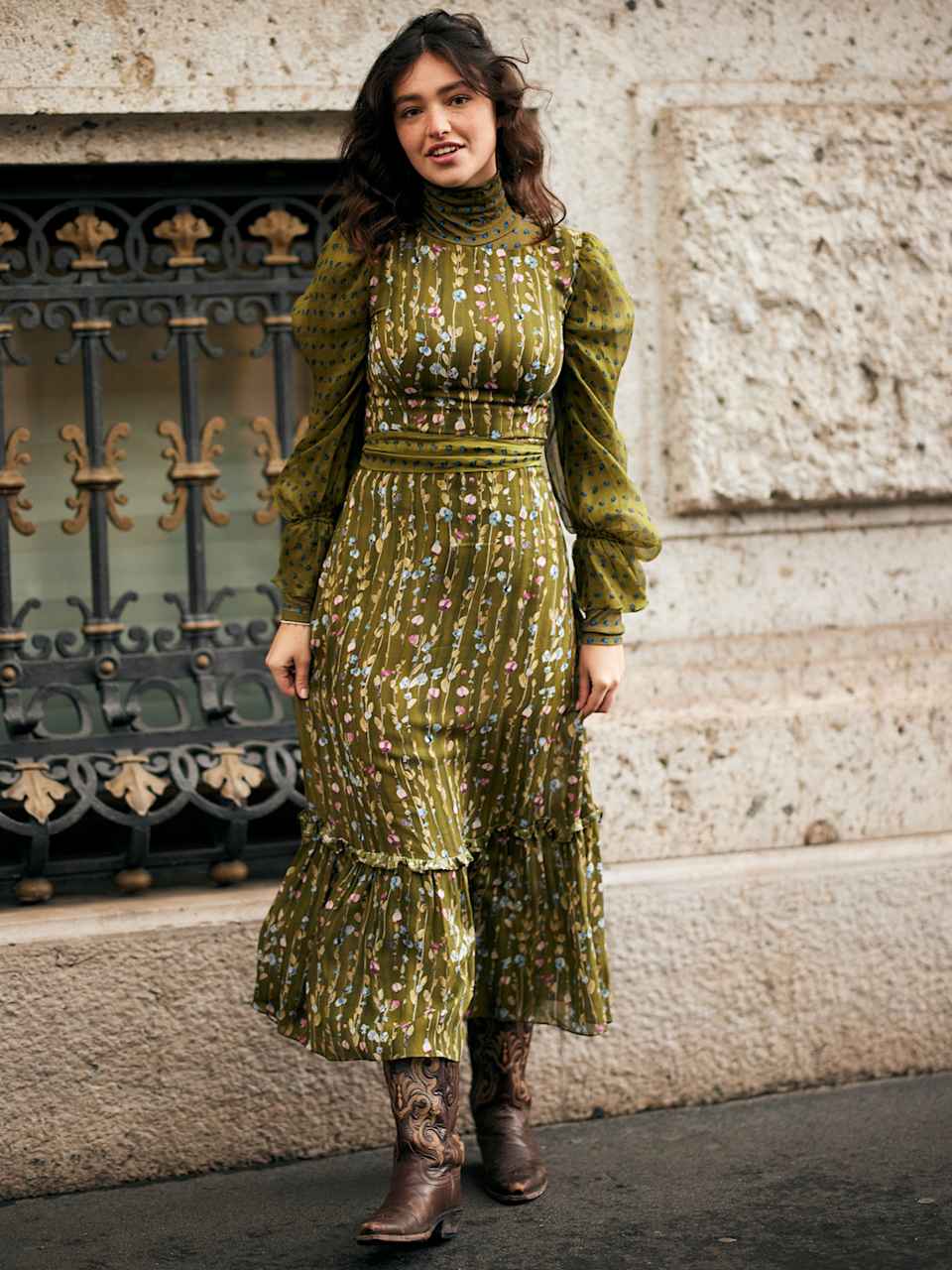 Frau trägt ein grünes Maxi-Kleid mit Blumenmuster und dunkelbraune Cowboy-Boots