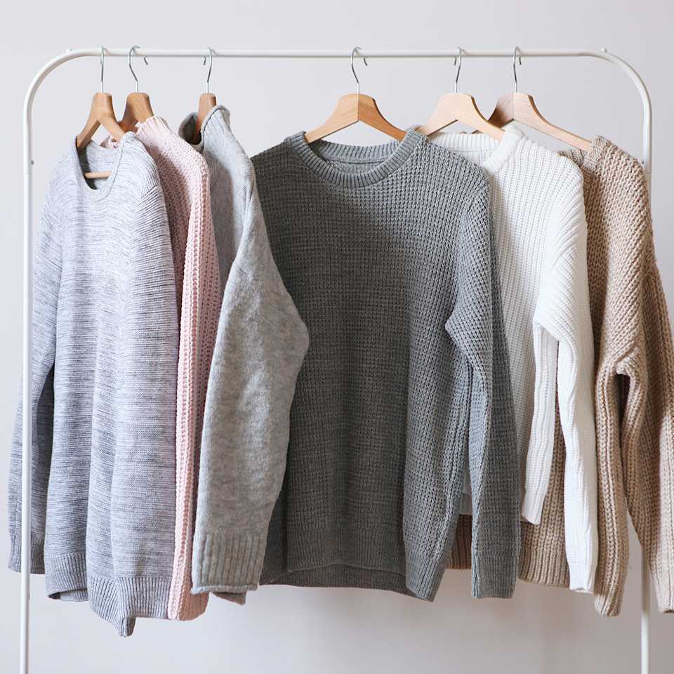 Strickpullover in verschiedenen Farben hängen an einer Kleiderstange