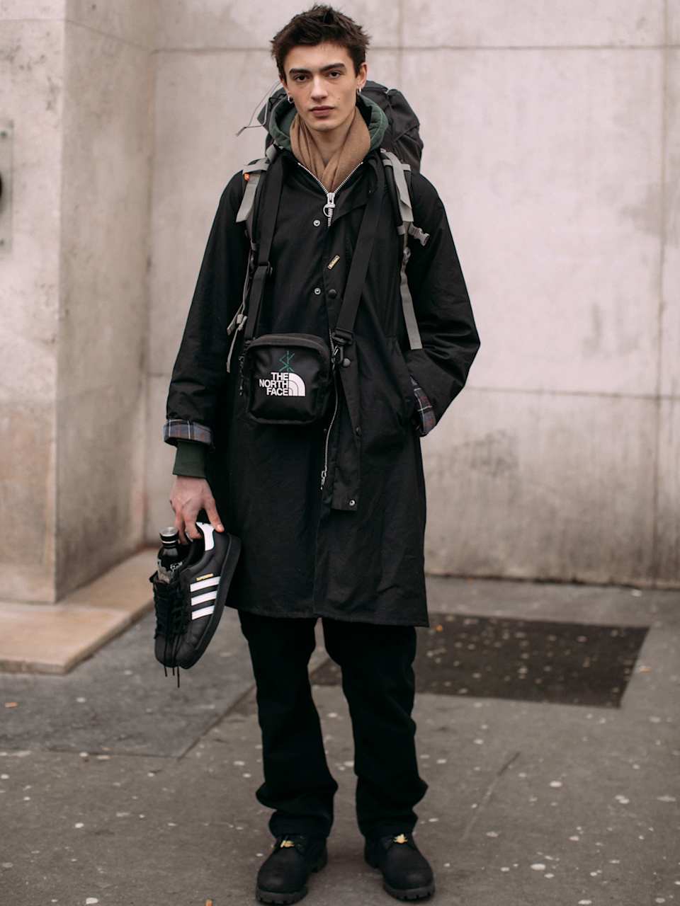 Mann trägt ein Streetstyle-Outfit in Schwarz mit Logos