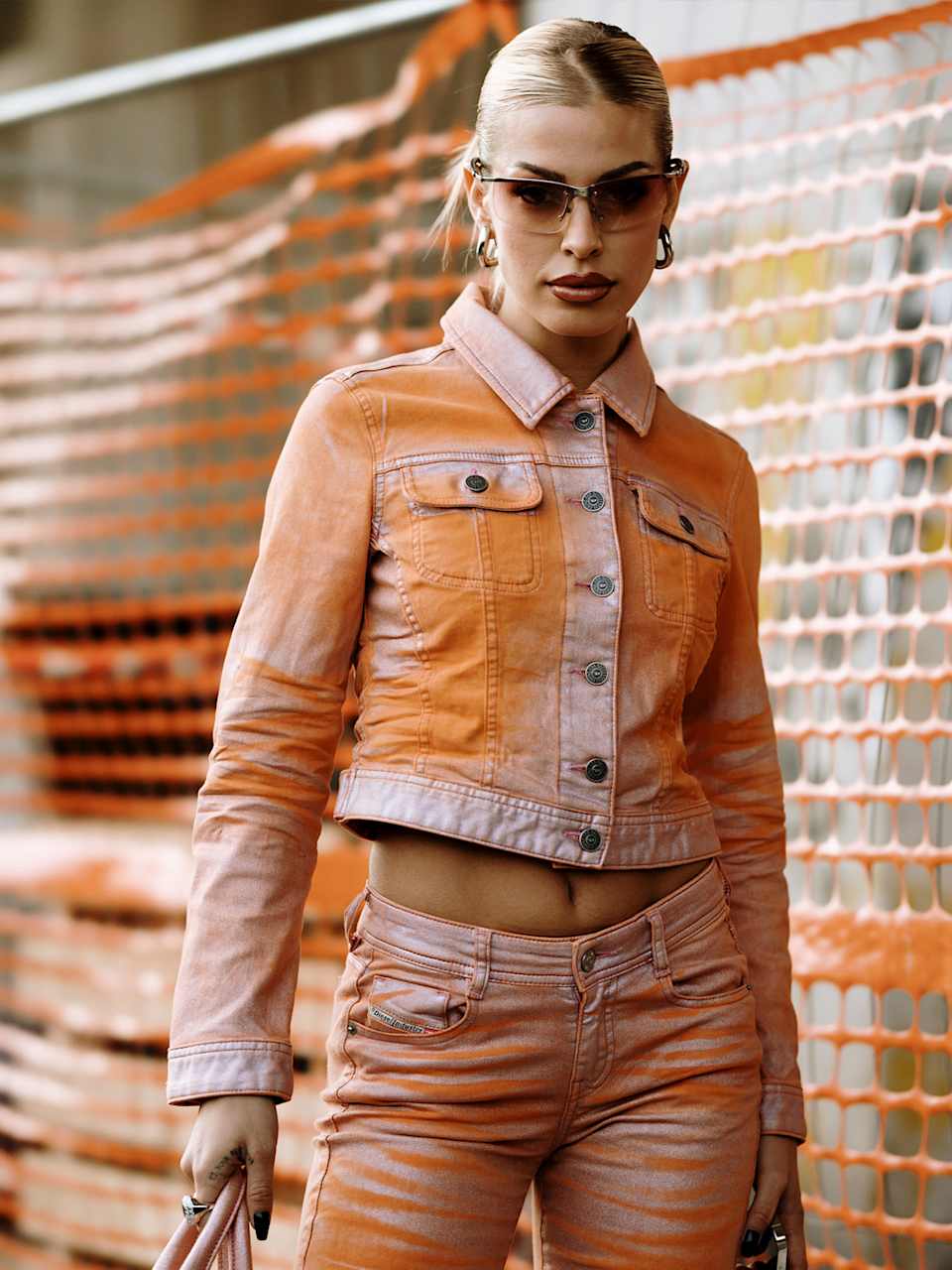 Frau trägt Racer-Sonnenbrille zu einem Jeans-Set mit Batikmuster