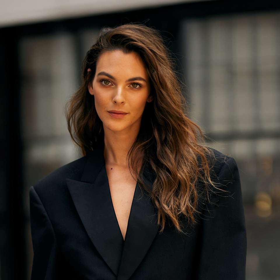 Brünette Frau mit langen, welligen Haaren trägt braun-goldenes Balayage