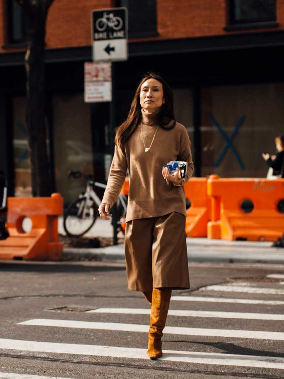 Frau trägt einen monochromen Look in Cognac bestehend aus Stiefeln, Leder-Bermuda 