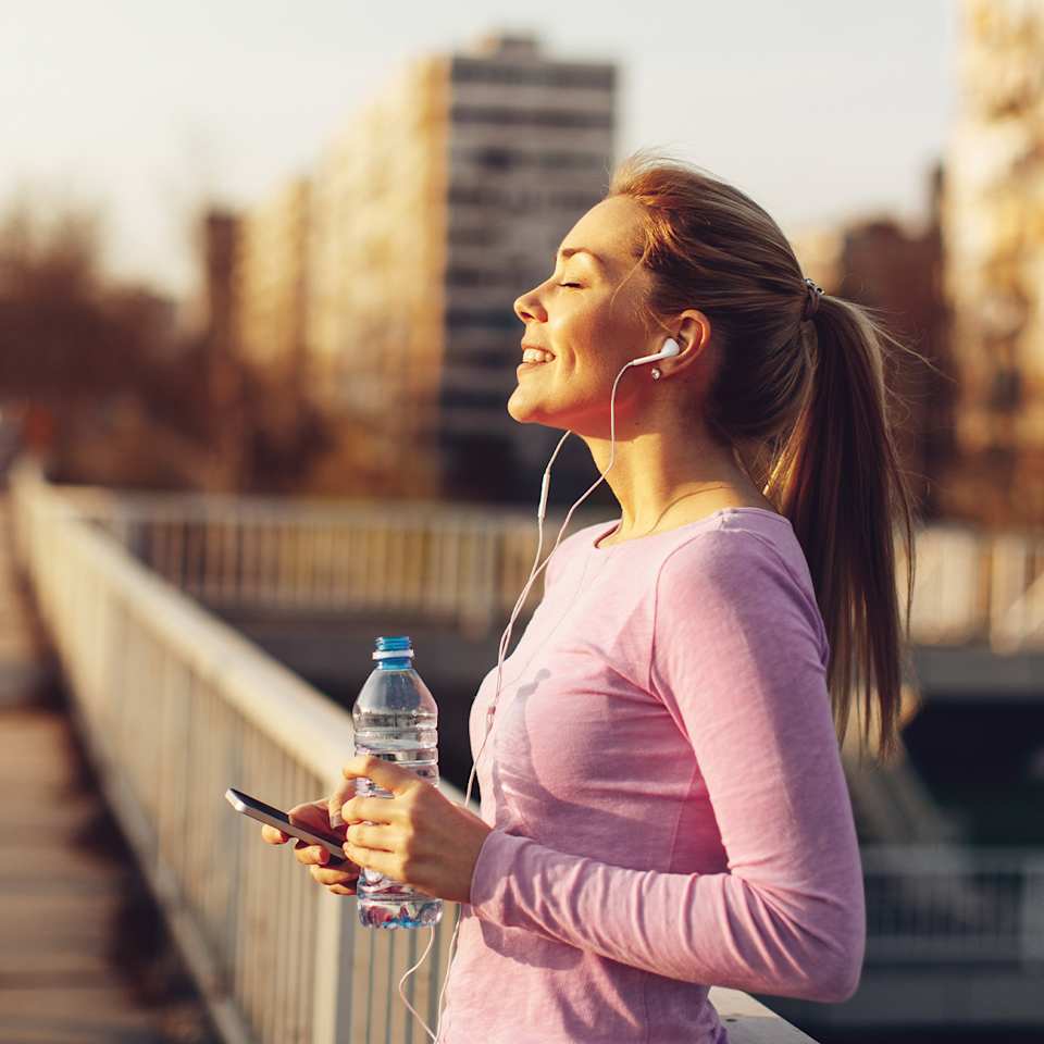 Läuferin mit Kopfhörern auf einer Brücke