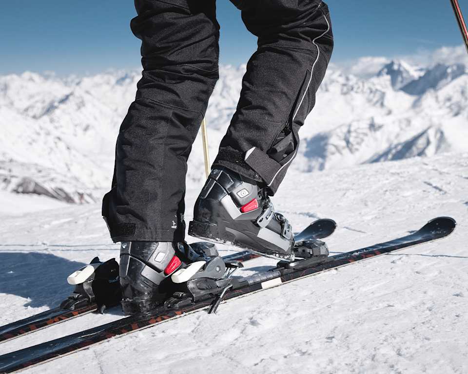 Nahaufnahme von Skischuhen die in die Skibindung steigen