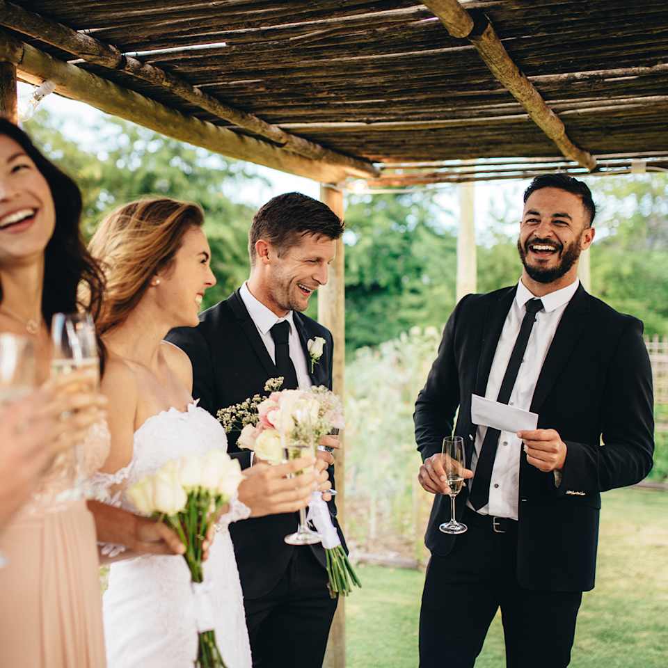 Hochzeitsgast in einem schwarzen Anzug mit Krawatte zusammen mit Brautpaar auf einer Hochzeit
