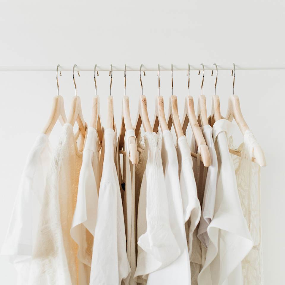 Mehrere weiße Oberteile hängen auf einer Kleiderstange