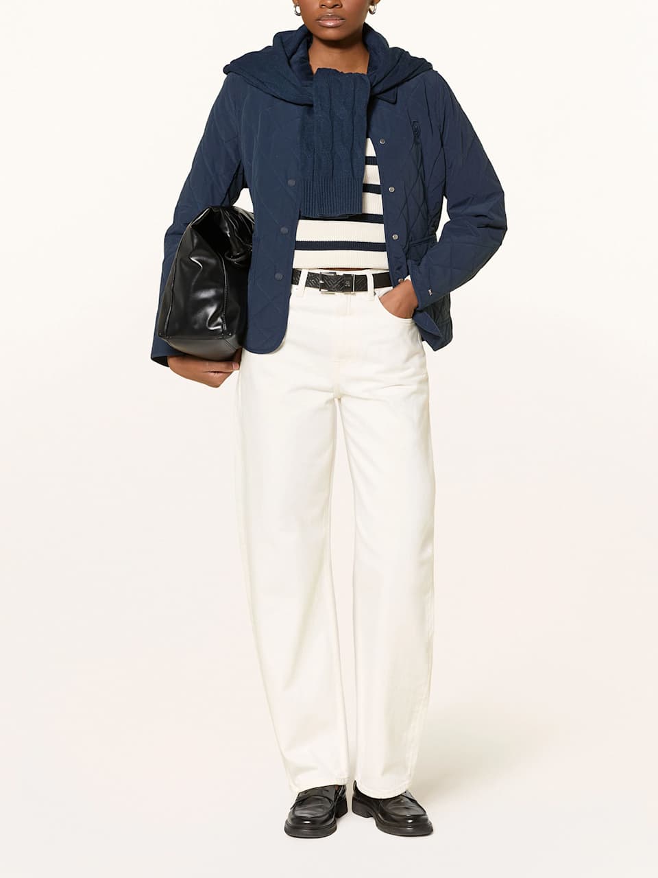 Eine Frau trägt eine weiße Mom-Jeans zu einer blauen Jacke