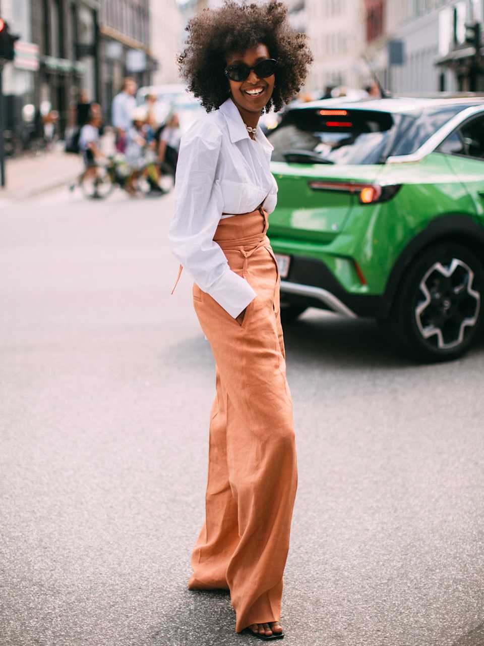 Frau trägt eine weiße Leinenbluse zu einer Hose in der Farbe Orange