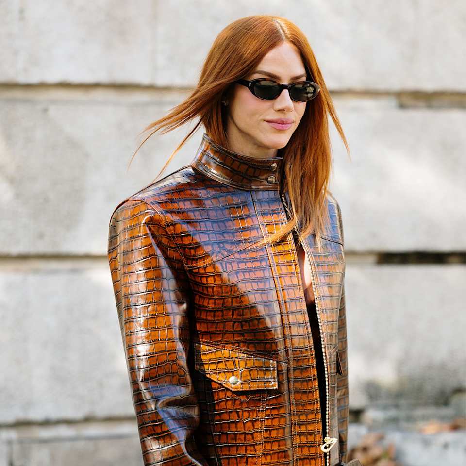 Frau trägt ihre kupferfarbenen, feinen Haare mittellang mit Mittelscheitel