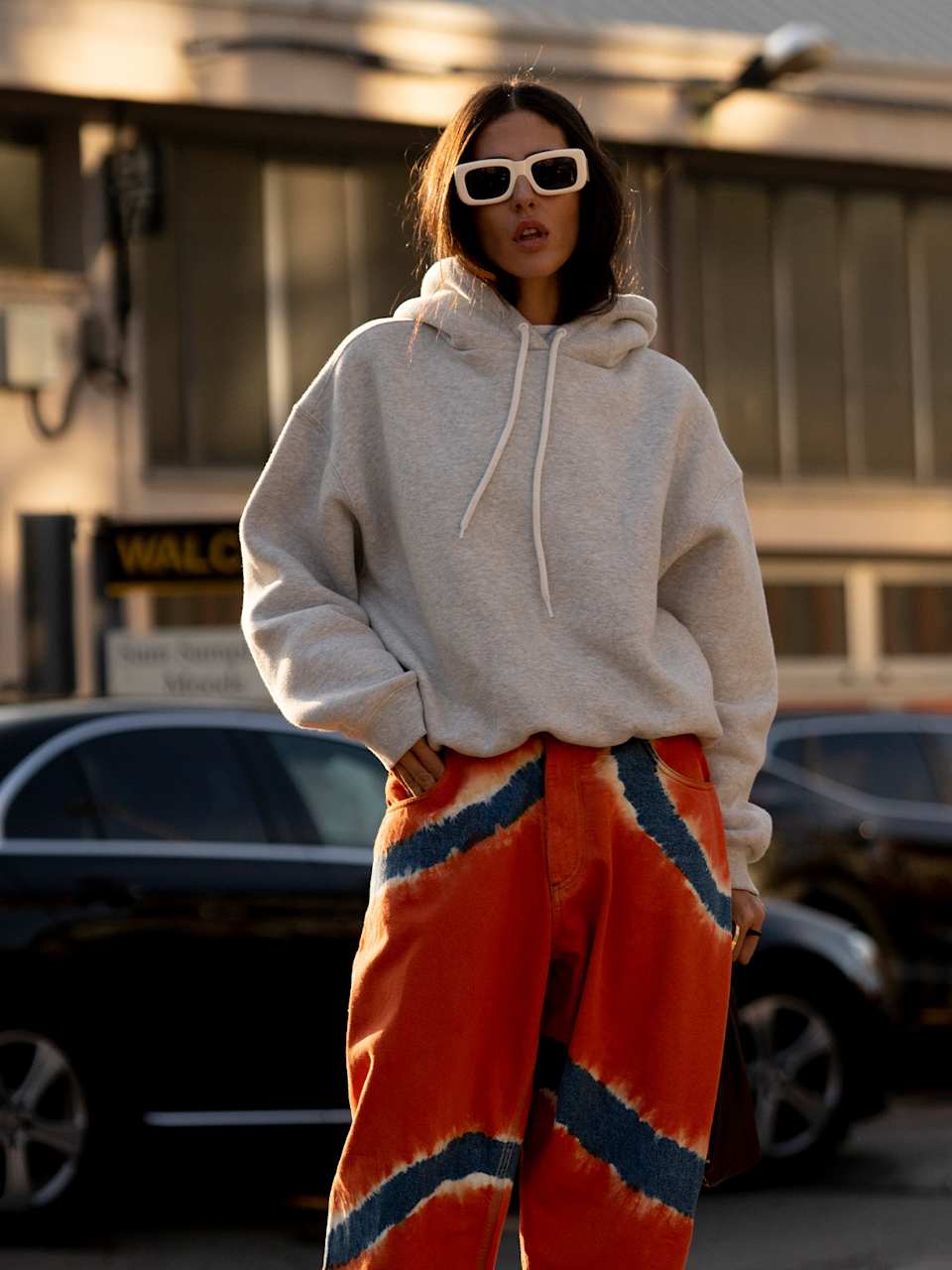 Frau trägt einen grauen Hoodie und eine bunte Hose in Rot und Blau