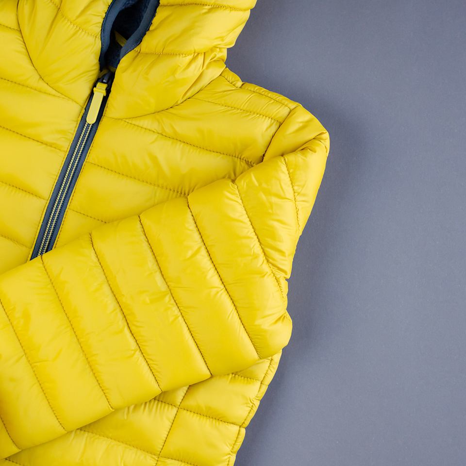 Gelbe Daunenjacke auf neutralem Hintergrund