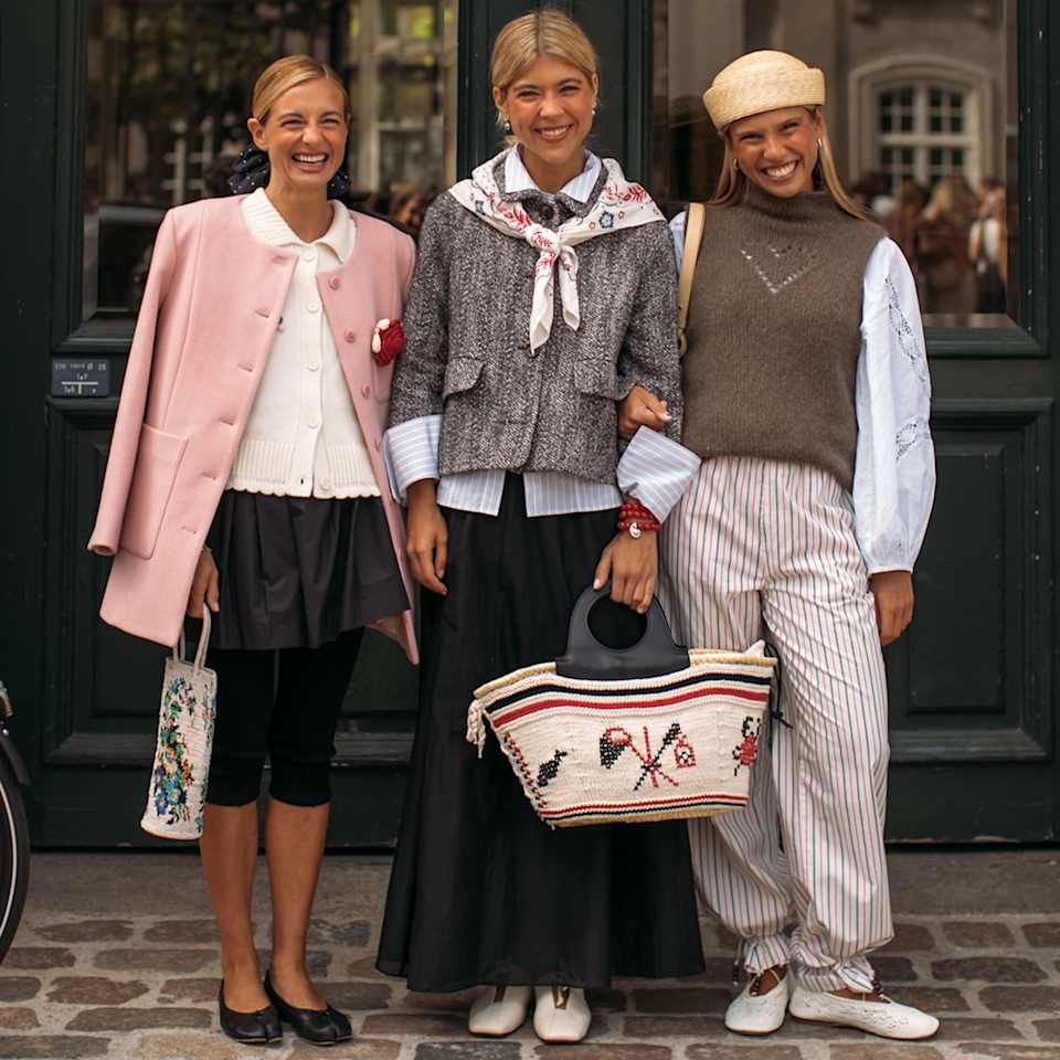 Drei Frauen stehen vor einer Haustür und tragen Frühlingsoutfits in den Farben Rosa und Grau