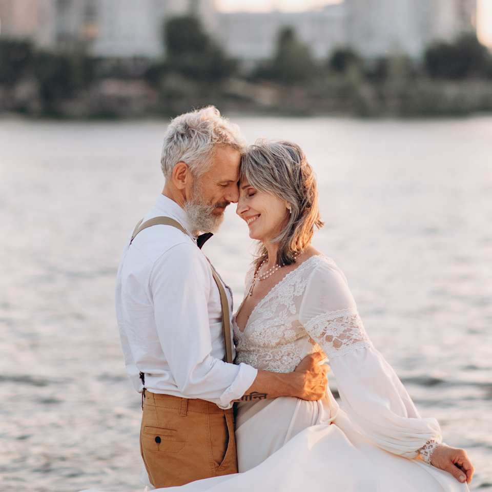 Frau und Mann umarmen sich in Silberhochzeits-Outfit 