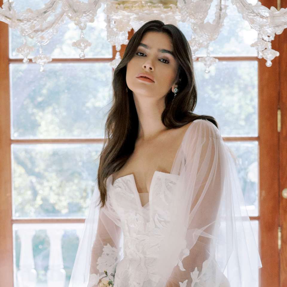 Braut in einem weißen Kleid und Strauß mit langen, offenen Haaren und großen Wellen