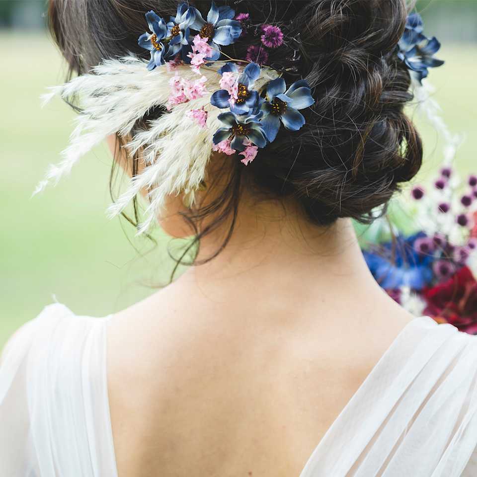 Braut hat einen bunten Blumenkranz in Ihrer Hochzeitsfrisur verarbeitet