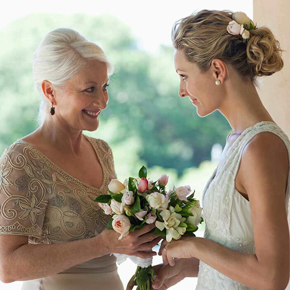 Brautmutter übergibt der Braut Blumen