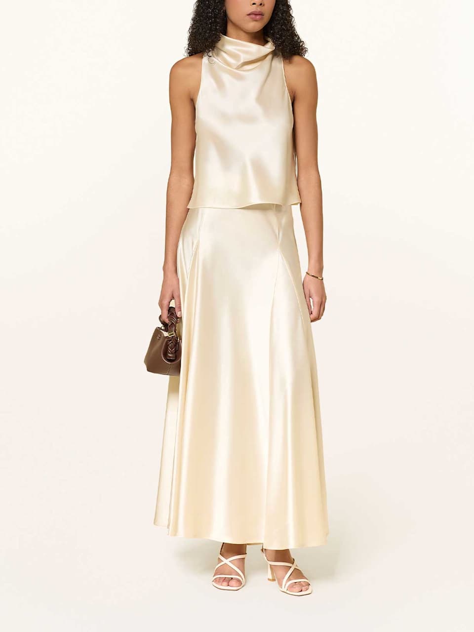 Frau trägt einen Zweiteiler aus hellem Satin bestehend aus Rock und Neckholder-Top