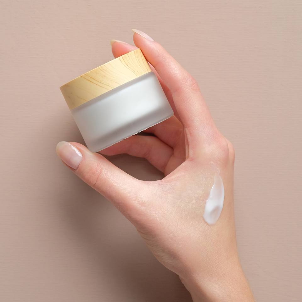 Nahaufnahme einer Hand die einen Creme-Tiegel in der Hand hält